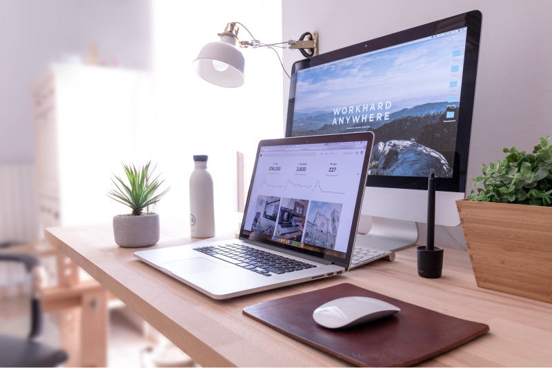 Laptop and a desktop on a table with "work hard anywhere" written on the desktop